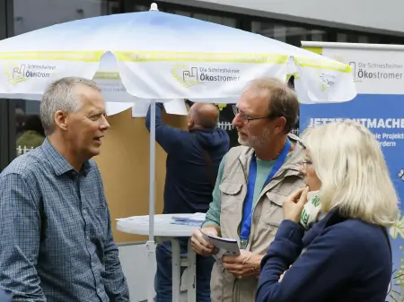 Standgespräch vor einem Sonnenschirm, auf dem «Schriesheimer Ökostrom» steht