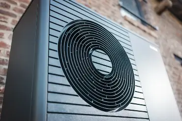 Wärmepumpe vor einer Backsteinwand