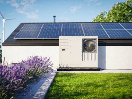 Modernes Haus mit Photovoltaik auf dem Dach und davor stehender Wärmepumpe