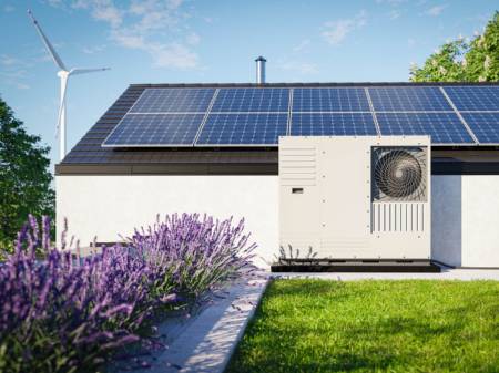 Modernes Haus mit Photovoltaik auf dem Dach und davor stehender Wärmepumpe