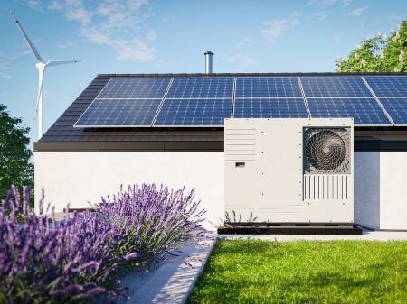 Modernes Haus mit Photovoltaik auf dem Dach und davor stehender Wärmepumpe