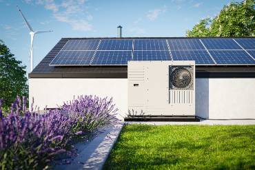 Zwei Monteure installieren eine Wärmepumpe im Garten