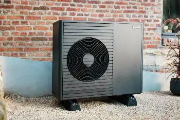 Wärmepumpe vor einer Backsteinwand