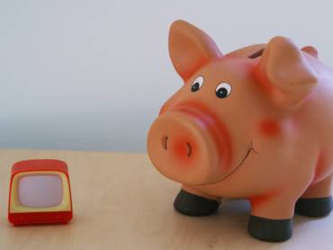 Sparschwein neben Spielzeugfernseher