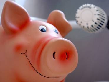 Sparschwein vor Heizungsthermostat