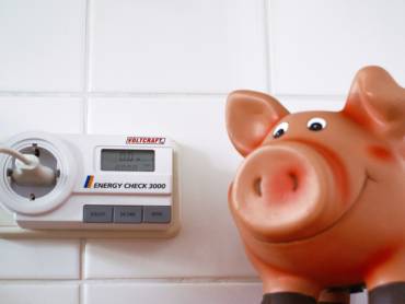 Sparschwein vor Strommessgerät