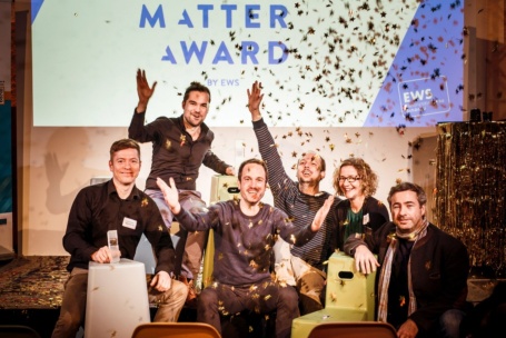 Eine Gruppe gutgelaunter Menschen am Rand einer Bühne wirft Goldsternchen in die Luft, hinter Ihnen erscheinen die Worte «Matter Award» auf einer Leinwand.