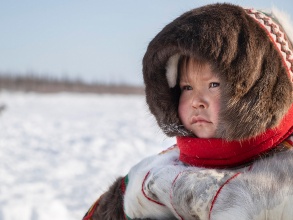 Ein Kind indigener Herkunft in Volkstracht in einer Winterlandschaft