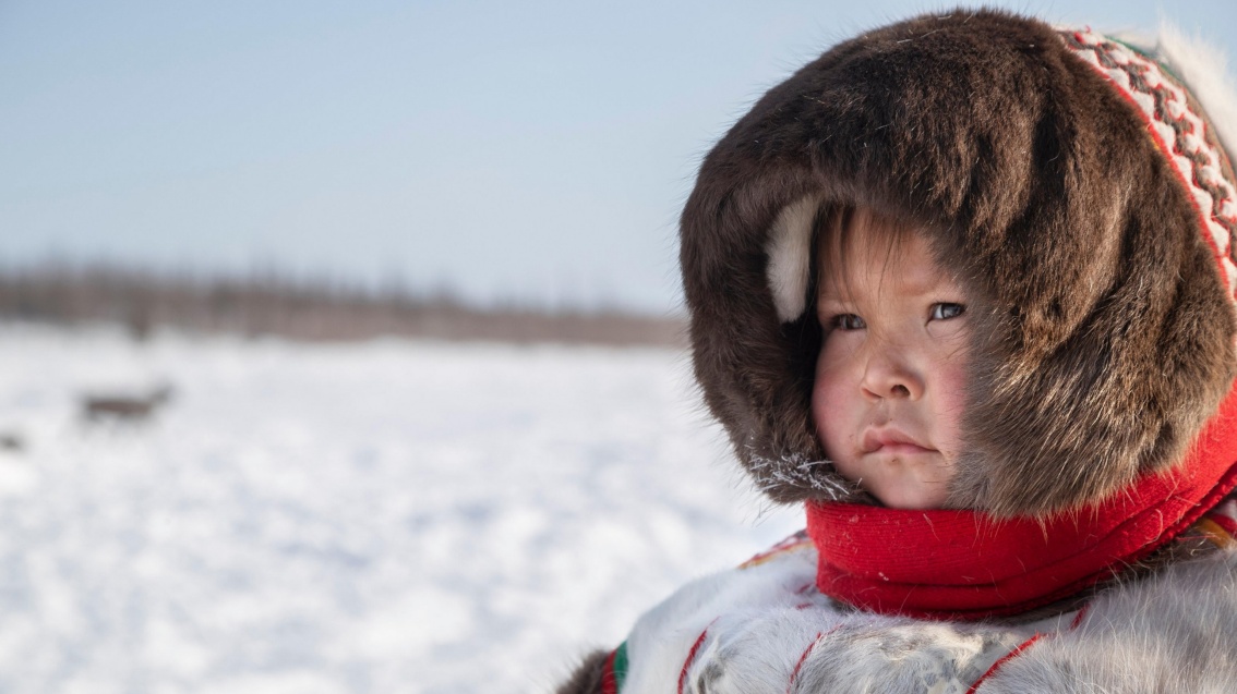 Ein Kind indigener Herkunft in Volkstracht in einer Winterlandschaft