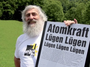 EWS-Mitgründer Michael Sladek zeigt ein Kampagnenplakat, darauf die Überschrift «Atomkraft – Lügen, Lügen, Lügen ...».