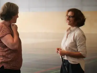 Zwei Personen unterhalten sich in einer Turnhalle