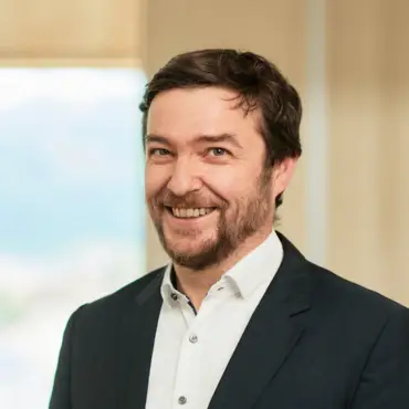 Portrait Sebastian Sladek vor einem Fenster und einer holzvertäfelten Wand