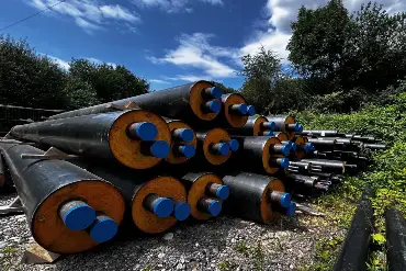 Ein Stapel Fernwärmerohre liegt an einer Baustelle bereit