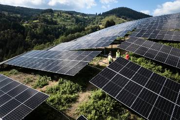 Der Solarpark Fröhnd aus Vogelperspektive, zwischen den Modulen sind drei Menschen in Warnwesten zu erkennen