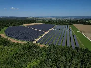 Luftaufnahme eines großen Solarparks, zwischen Wald und Wiesen gelegen