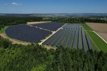Luftaufnahme eines großen Solarparks, zwischen Wald und Wiesen gelegen