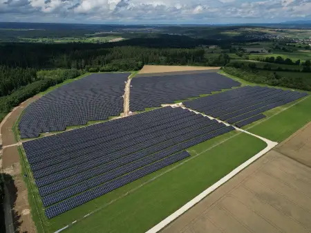 Luftaufnahme eines großen Solarparks, zwischen Wald und Wiesen gelegen