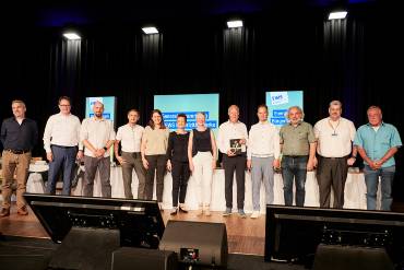 Gruppenfoto von 12 Personen auf einer Bühne nebeneinander aufgereiht