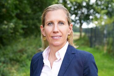 Eine Frau im Business-Look steht im Grünen auf einem Pfad 