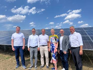 Sechs Menschen stehen nebeneinander auf einem Feld vor Solarpanels im Solarpark Trichtingen.