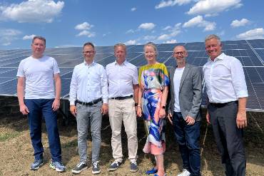 Sechs Menschen stehen nebeneinander auf einem Feld vor Solarpanels im Solarpark Trichtingen.