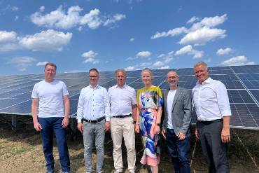 Sechs Menschen stehen nebeneinander auf einem Feld vor Solarpanels im Solarpark Trichtingen.