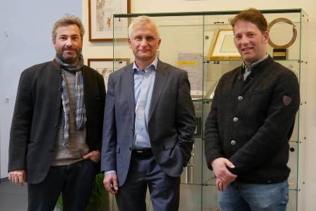 Gruppenfoto der Gesprächsteilnehmer vor einer Vitrine mit Auszeichnungen für die EWS