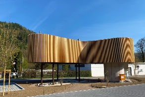 Foto eines Gebäudes mit geschwungenen Formen und Holzverkleidung vor klarem Himmel