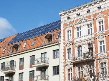 Ansicht eines gründerzeitlichen Mietshauses, auf dem Dach sind PV-Module installiert