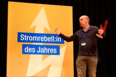 Ein Mann steht auf einer Bühne und hält eine Trophäe in der Hand