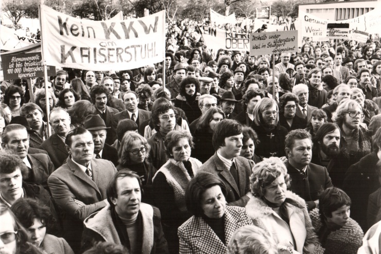 Archivaufnahme einer Demonstration gegen Atomkraftwerke in Wyhl, ein großes Transparent zeigt die Aufschrift "Kein KKW am Kaiserstuhl" 