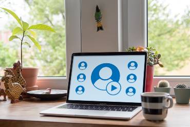 Ein Laptop vor dem Fensterbrett, auf seinem Bildschirm sind Personen-Icons