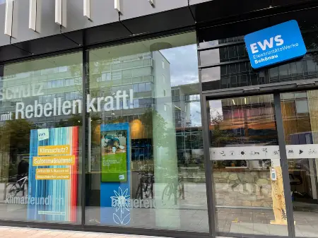 Ein Bürogebäude mit EWS-Leuchtschild, an dem in Folienschrift das Wort «Rebellenkraft» zu erkennen ist.