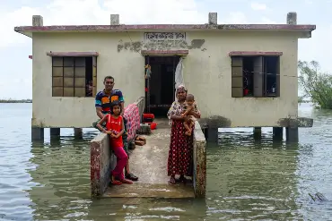 Eine pakistanische Familie steht vor einem überschwemmten Haus