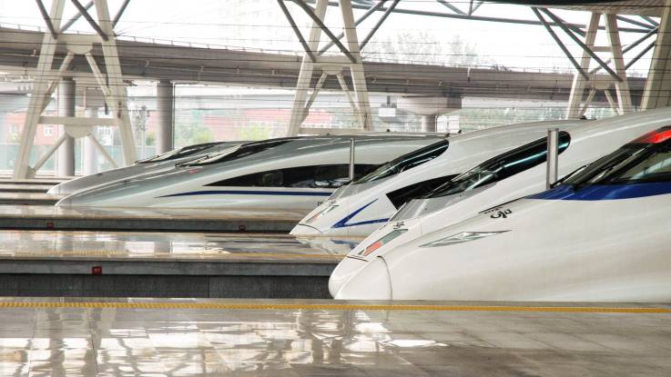 An blitzblank gescheuerten Bahnsteigen stehen fünf Züge, die aerodynamisch geformten Zugköpfe versetzt hintereinander gestaffelt.