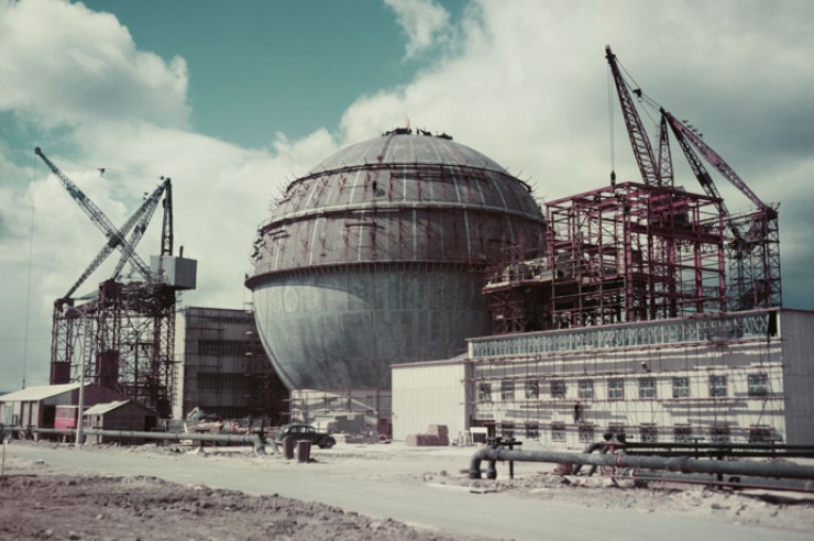 Farbfoto in deutlich antiquiertem Kolorit zeigt die Baustelle des Atomkraftwerkes, der Kühlbehälter ist kugelrund.