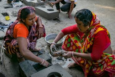 Zwei Frauen in indischer Kleidung bauen einen Lehmherd.