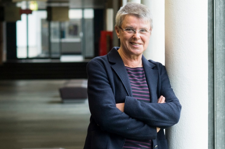 Ingrid Schmale steht lächelnd und mit verschränkten Armen auf einem Flur