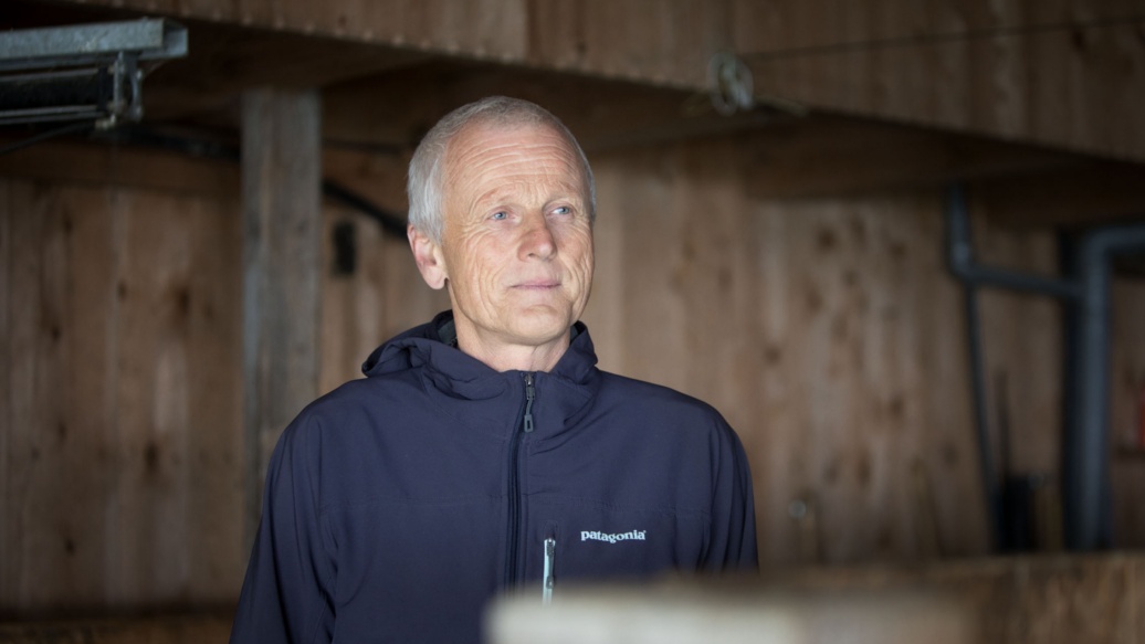 Ein alterer Mann mit blauem Kapuzenpullover in einer Scheune