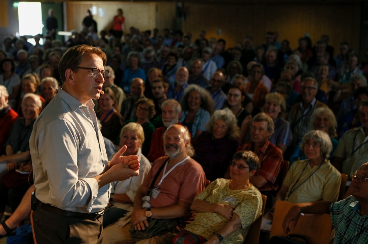 Prof. Jörg Probst im Vordergrund, vergnügtes Publikum im Hintergrund
