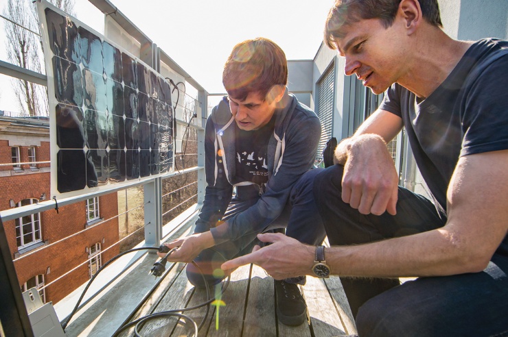 Zwei junge Männer bei der Montage eines Solarmoduls auf einem Balkon