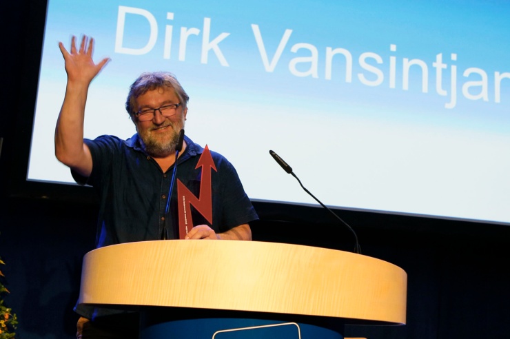 Lachender Mann winkt ins Publikum 