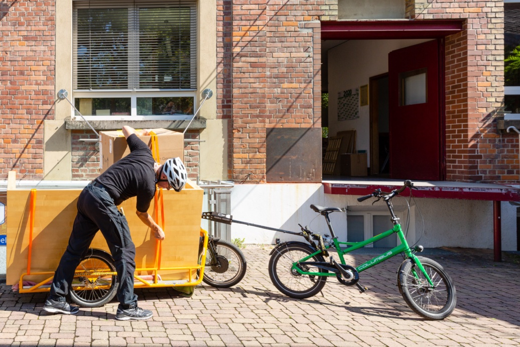 Auf einem Hof steht ein kleines Fahrrad mit einem großen Anhänger.
