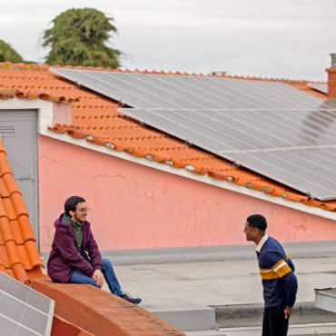 Aus einem Fenster in der Lissaboner Altstadt lehnt sich freundlich lachend eine Frau.