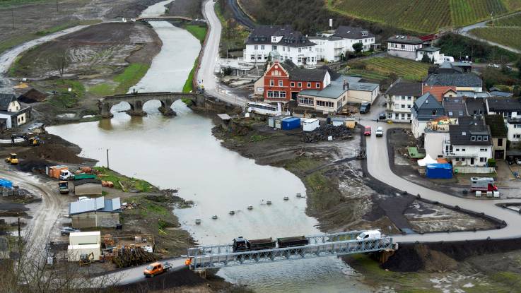 Luftbild von dem zerstörten Ort, den Trümmern einer alten Steinbrücke und den bereits installierten Behelfsbrücken.