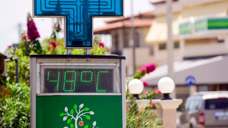 Eine Anzeigetafel vor sonnenbeschienenen Gebäuden zeigt 48 Grad Celsius an. 