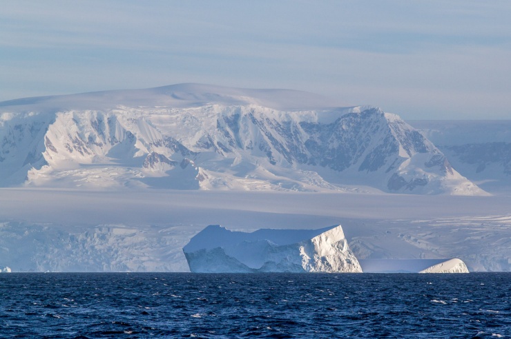 Eisberge im tiefblauen Wasser, dahinter schneebedeckte Berge