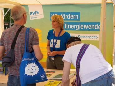 Hinter dem Stand der EWS horcht eine blonde Frau aufmerksam den Fragen der Besucher.