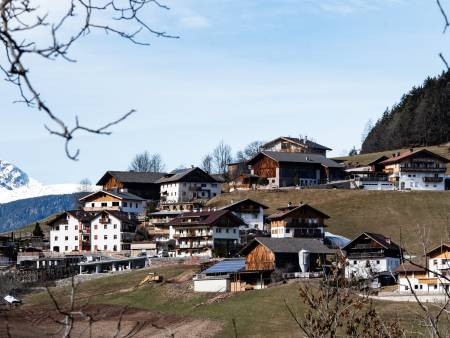 Blick in ein malerisches Alpental, im Hintergrund schneebedeckte Berge.