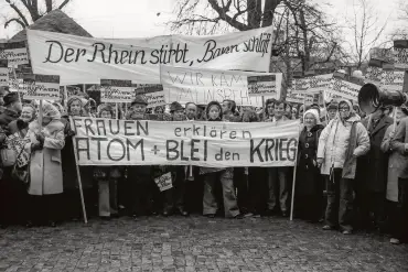 Eine Schwarz-Weiß-Aufnahme zeigt Demonstrantinnen und Demonstranten aller Altersklassen mit zahlreichen Bannern und Schildern. 